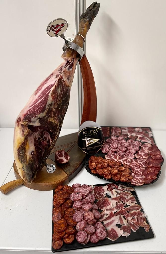 Jamón ibérico en el jamonero junto a una tabla de embutidos